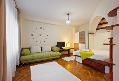a living room with a couch and a clock on the wall at Green Apartment in Budapest