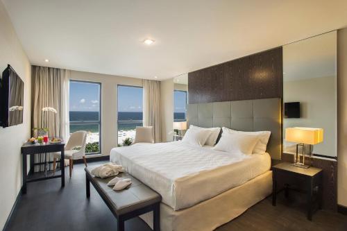 a bedroom with a large white bed and a desk at Windsor California Copacabana in Rio de Janeiro