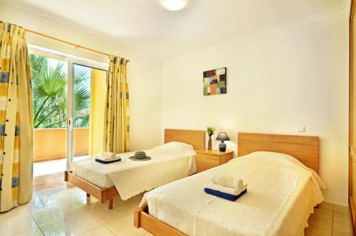 a bedroom with two beds and a large window at Jardim da Meia Praia Resort in Lagos
