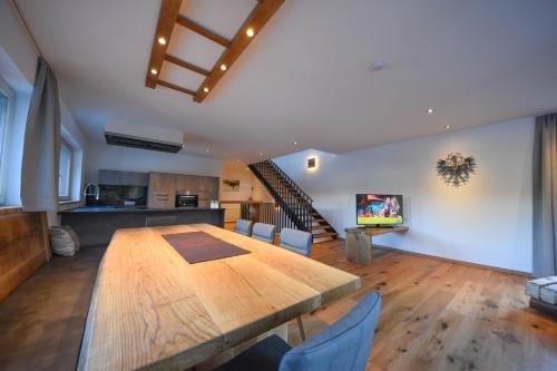 a dining room with a large wooden table and a kitchen at Alpenzeit in Ladis
