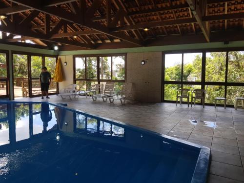 a swimming pool in a house with a person standing next to it at Residencial Pousada do Serrano in Gramado
