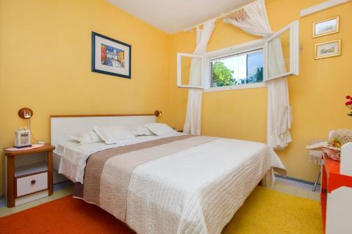 a yellow bedroom with a bed and a window at Apartment Jadrija in Šibenik