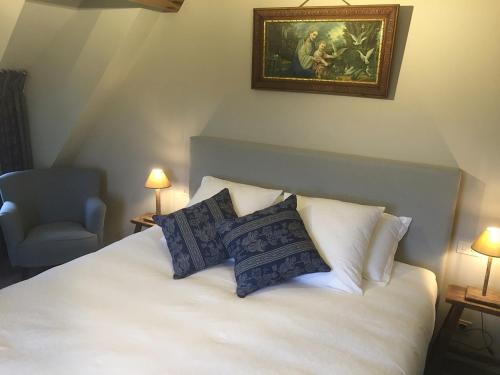 a bedroom with a bed with pillows and a painting on the wall at de Gasterie in Koksijde