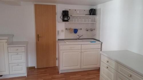 uma cozinha com armários brancos e um lavatório em Baunaeck em Baunatal