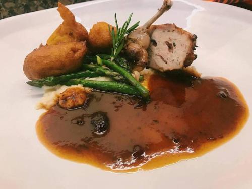 a plate of food with meat and vegetables and gravy at Serendipity Country House & Restaurant in Wilderness