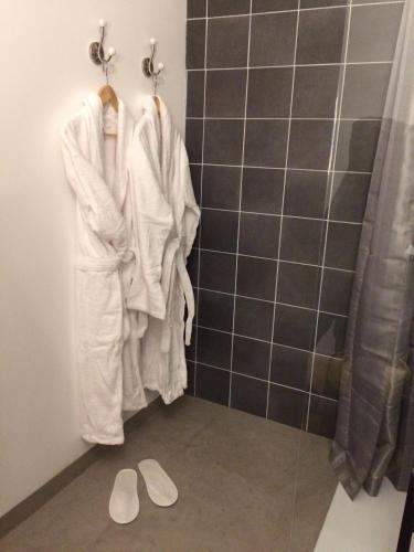 La salle de bains est pourvue d'une douche, de peignoirs blancs et de chaussons. dans l'établissement Les Chambres du Mad, à Henvic