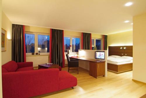 a hotel room with a red couch and a bed at Trend Hotel in Banzkow
