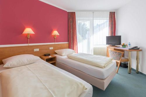 a hotel room with two beds and a desk at Aparthotel Berlin in Bad Nenndorf