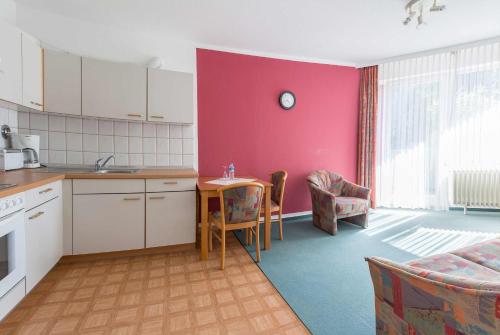 a kitchen with pink walls and a table and chairs at Aparthotel Berlin in Bad Nenndorf