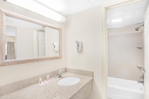 a bathroom with a sink and a mirror at Days Inn by Wyndham Springfield/Phil.Intl Airport in Springfield