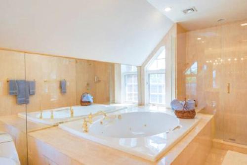 a large bathroom with two tubs and a window at Villa Victoria - Cozy Hamptons Villa in Bridgehampton