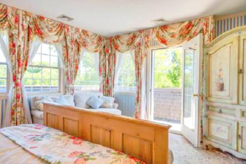 een slaapkamer met een bed, een bank en ramen bij Villa Victoria - Cozy Hamptons Villa in Bridgehampton
