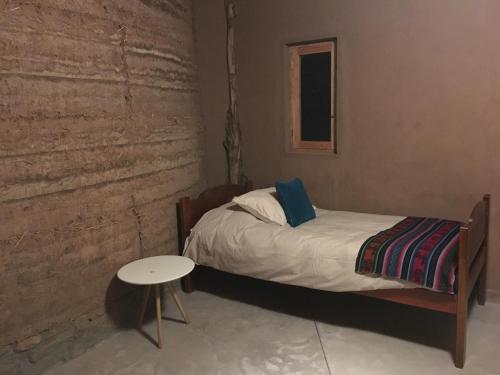 a small bedroom with a bed and a table at Vernacular Lodge in San Pedro de Atacama