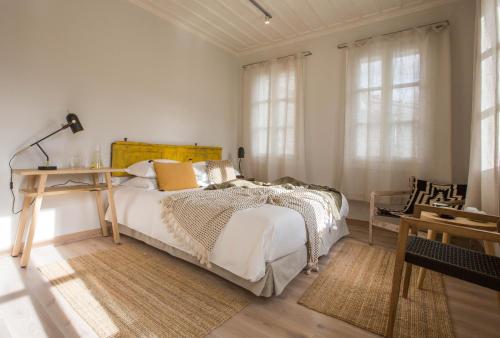 a bedroom with a bed and a desk and windows at Amymone Suites in Nafplio