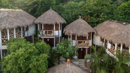 a group of huts with thatched roofs and trees at Cabañas Biuzaa in Zipolite