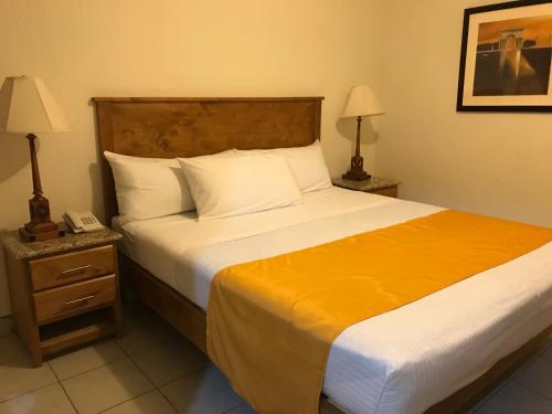 a bedroom with a large bed with a phone on a night stand at Hotel Guillen Jr in Tijuana