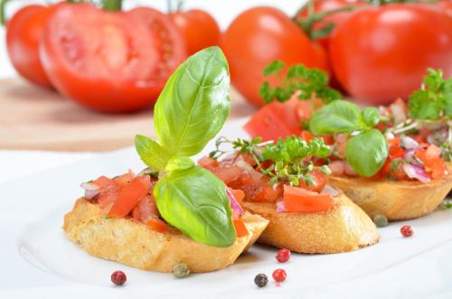 a plate of appetizers with tomatoes and basil on it at Bankton Rooms & Lodges in Livingston
