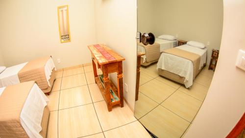 a view of a room with two beds and a table at Hotel Winner in Barretos