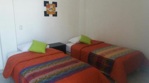 two beds with green pillows in a room at La Maison de Lydia in Nazca