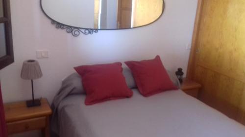 a bedroom with a bed with two red pillows and a mirror at Casa Pilar in Playa Honda
