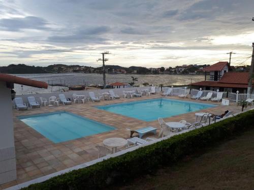 a large swimming pool with chairs at Cantinho do Village in São Pedro da Aldeia