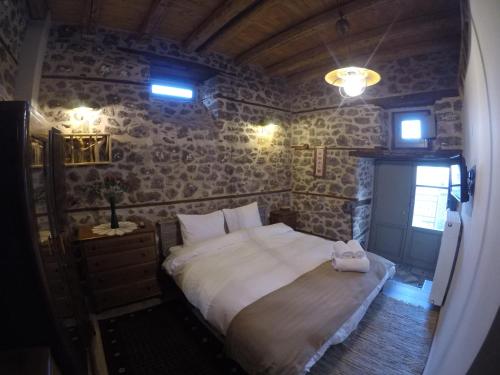a bedroom with a large bed in a room with stone walls at Bayiri Petit Pension in Litochoro