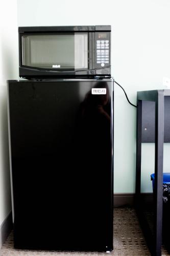 a microwave sitting on top of a black refrigerator at United College in Waterloo