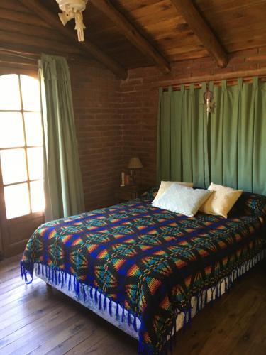 1 dormitorio con 1 cama grande y cortinas verdes en Cabaña Aires del Bosque en Balneario Mar Azul