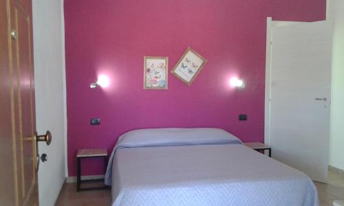 SennarioloにあるAlma Bed & Breakfastのピンクの壁のベッドルーム(ベッド付)