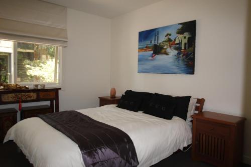 a bedroom with a bed and a painting on the wall at Lorne Holiday House in Lorne