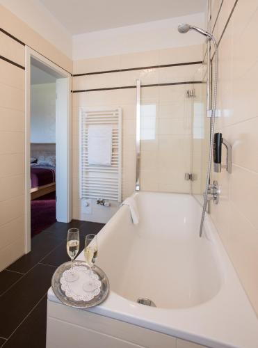 a bathroom with a tub with two glasses of wine at Hotel Restaurant Zum Heidekrug in Bersenbrück