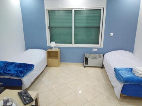 two beds in a room with a window at Studios Taha in Rabat