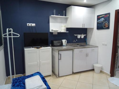 a kitchen with white cabinets and a blue wall at Studios Taha in Rabat