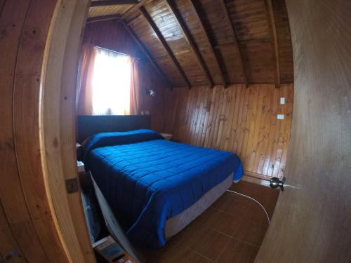 a small bed in a wooden room with a window at Hecmar 2 in Pichilemu