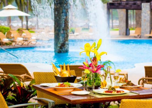 een tafel met borden eten naast een zwembad bij Pierre Mundo Imperial Riviera Diamante Acapulco in Acapulco
