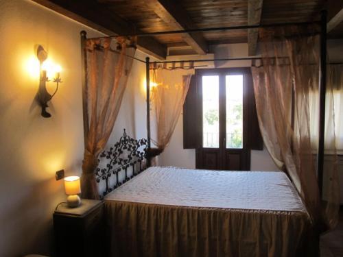 a bedroom with a canopy bed with a window at Residenza D'Epoca Le Pisanelle in Manciano