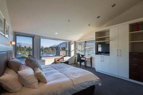 a bedroom with a large bed with a large window at Shotover Penthouse & Spa by Staysouth in Queenstown
