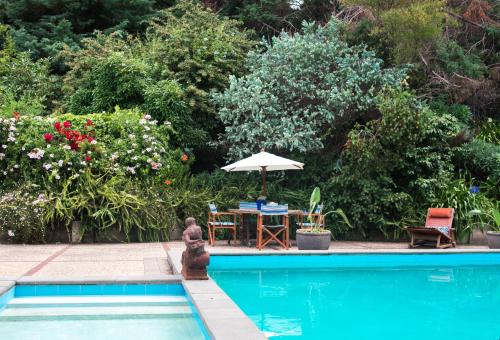 a man sitting by a swimming pool with a table and an umbrella at Seahurst Apartment in Eskdale