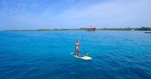 a person riding a paddle board on top of a body of water at Hotel Punta Faro in Isla Mucura