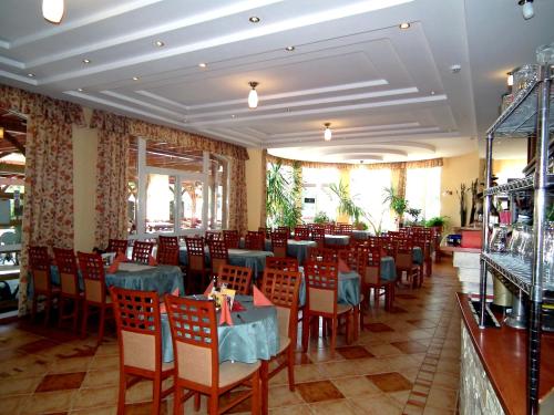 a restaurant with tables and chairs in a room at Hotel Járja in Hajdúszoboszló
