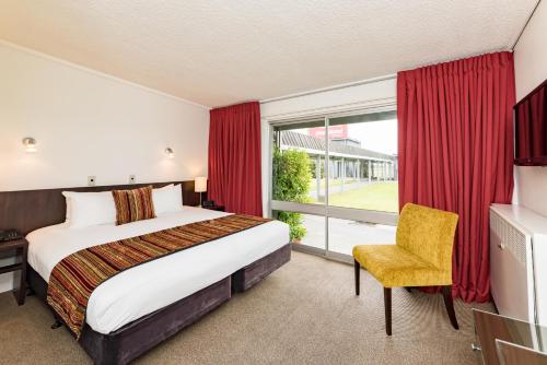 a hotel room with a bed and a chair at Heartland Hotel Haast in Haast