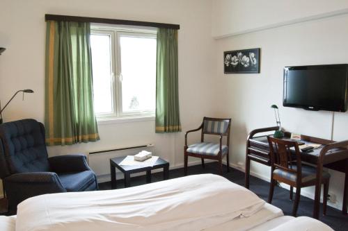 a hotel room with a bed and chairs and a tv at Moi Hotel in Moi