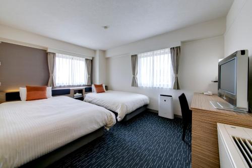 a hotel room with two beds and a flat screen tv at Plaza Hotel Toyota in Toyota