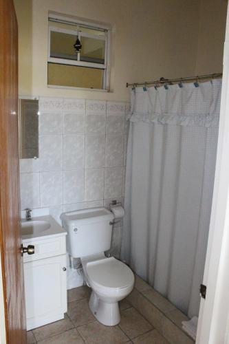 a white bathroom with a toilet and a sink at The Relax Inn in Saint Georgeʼs