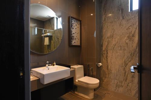 a bathroom with a sink and a toilet and a mirror at Vangohh Eminent Hotel & Spa in Bukit Mertajam