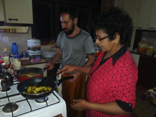 a man and a woman preparing food in a pan on a stove at Evergreen in Kandy
