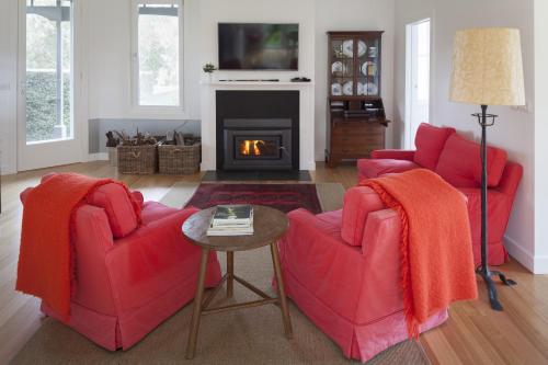 a living room with two red chairs and a fireplace at The Cottage at Bolobek in Macedon