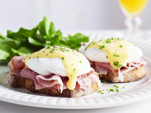 a sandwich with ham and eggs on a plate with greens at Golden Caves - Bed and Breakfast in Takaka