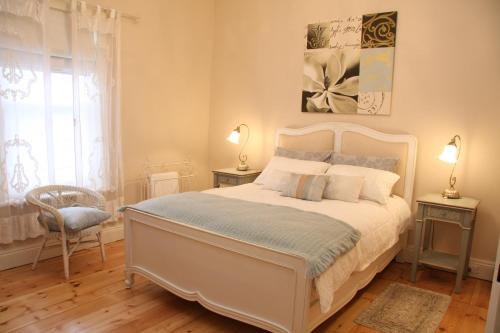 Azalea Cedar-Rose Barossa Valley Villa في ليندوخ: غرفة نوم بسرير ابيض وكرسي