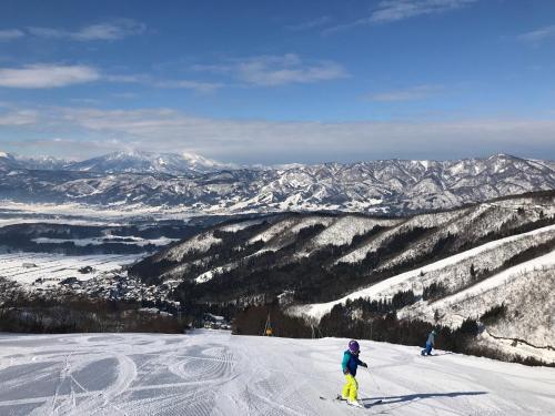 two people are skiing down a snow covered mountain at Schanze Nozawa in Nozawa Onsen